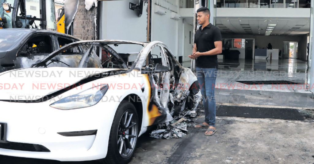 HSM Auto CEO Mikhail Hosein looks at vehicles damaged in a firebomb attack at his business compound in
Chase Village, Chaguanas, on Thursday. PHOTOS BY Aya nna Kinsale