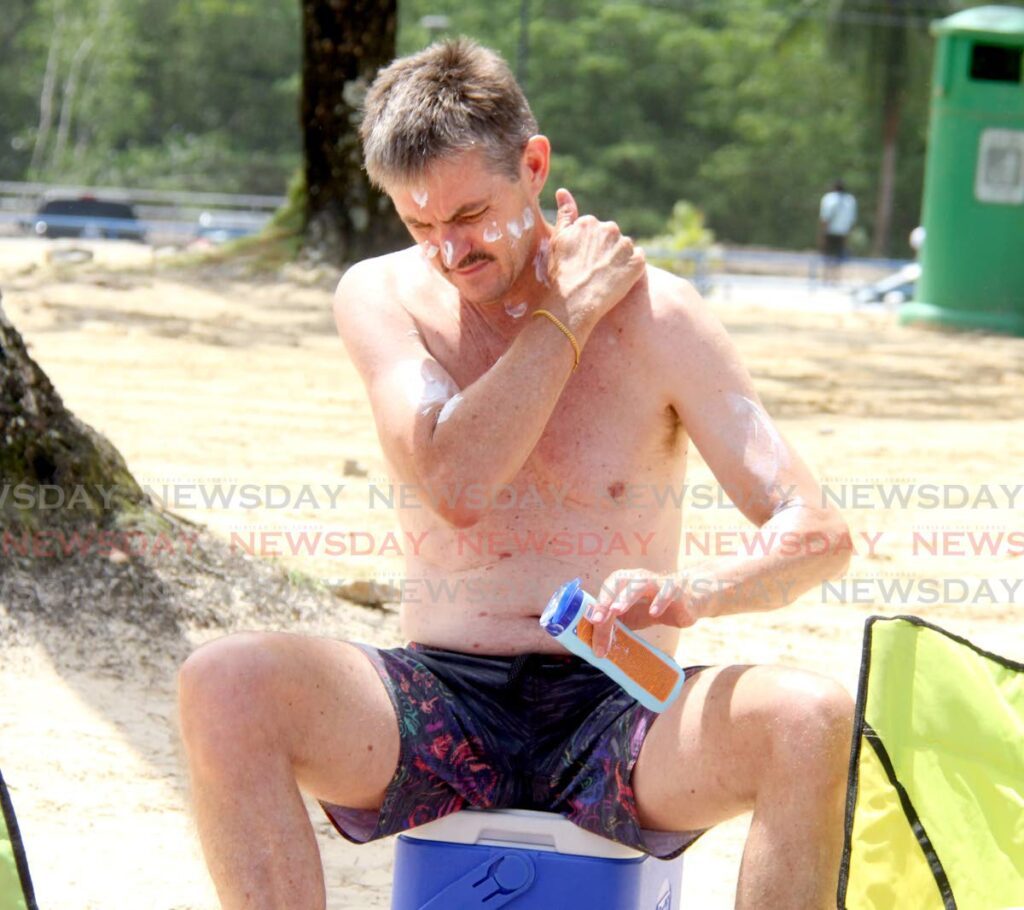 File: This man rubs sun lotion on his skin at Maracas Beach to prevent sun burn. - Ayanna Kinsale