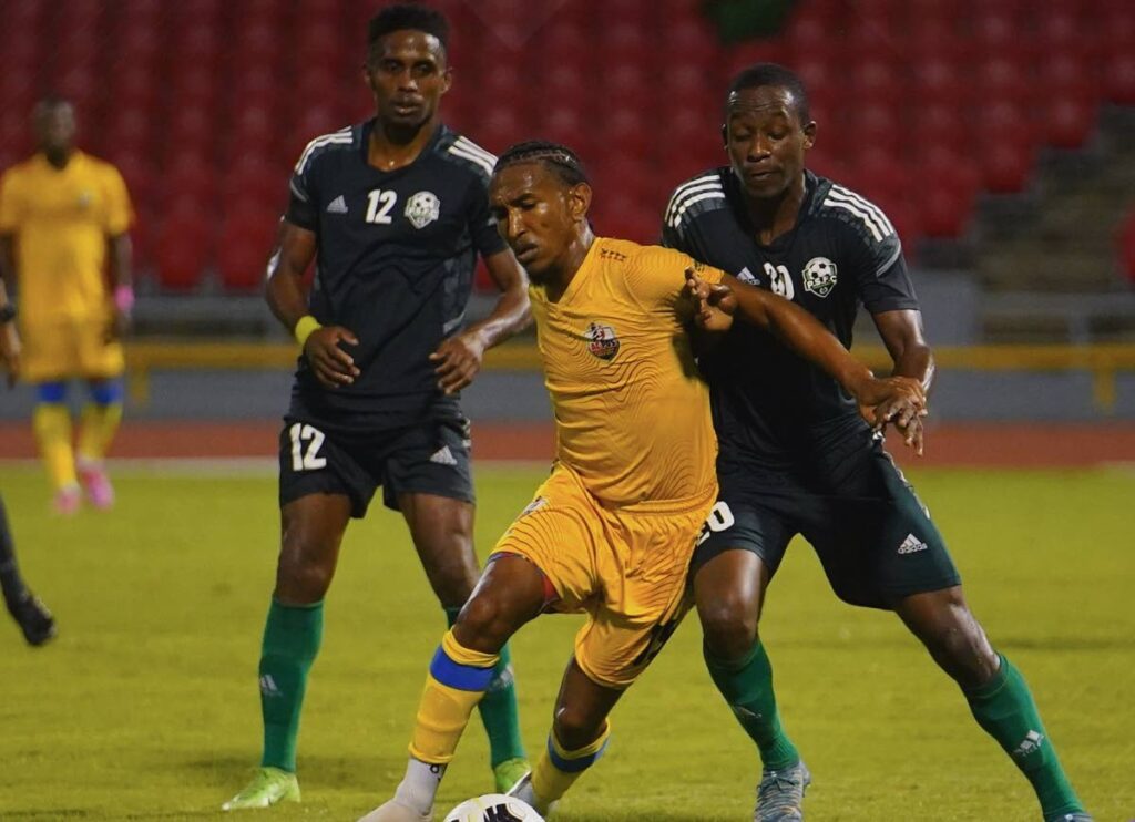 AC Port of Spain midfielder John-Paul Rochford, centre, shields the ball against Prisons.  - TTPFL