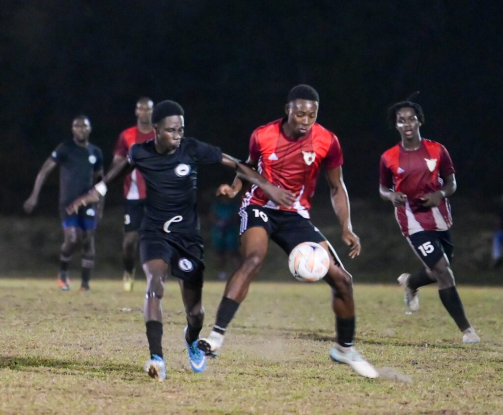 A Kings United player, left, battles his Eagles FC rival for the ball in the Moriah Village Football League final on May 4.