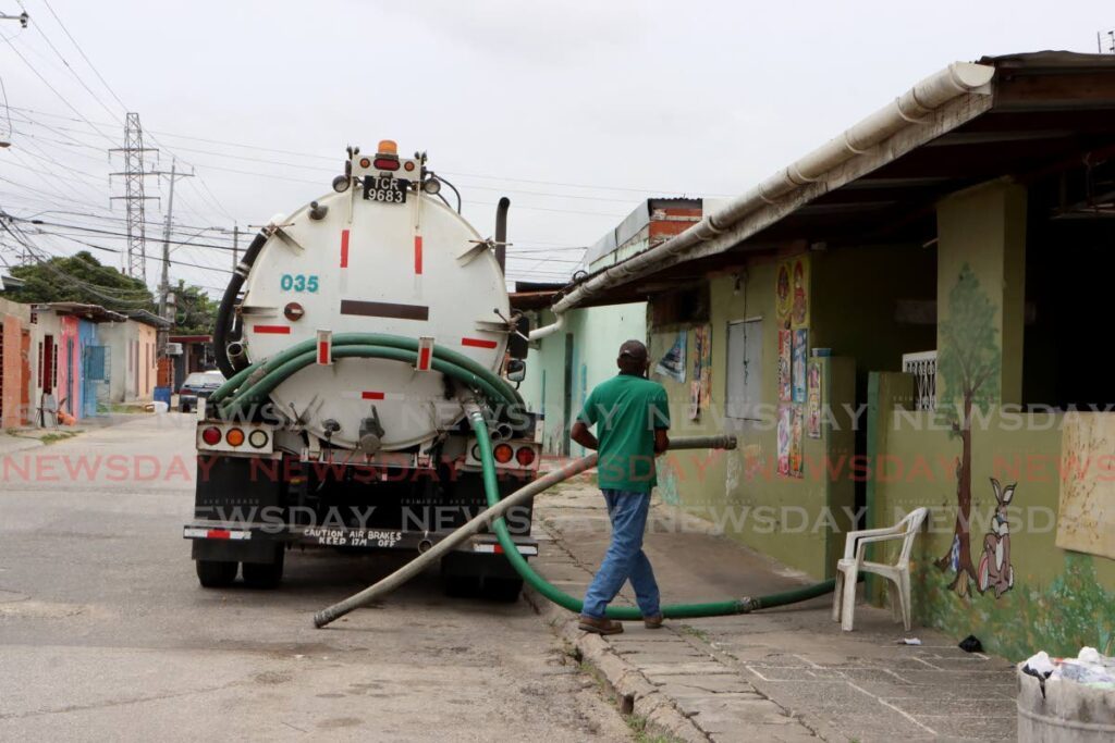 A WASA employee prepares to clean a cesspit at a house at Beetham Gardens on Friday. - Angelo Marcelle