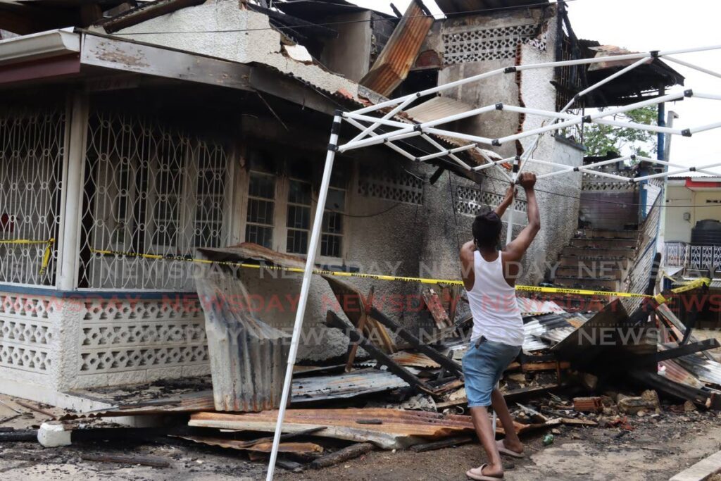 Mac Newton erects a tent in the yard of a San Juan house that was destroyed by fire on Thursday.  - Faith Ayoung