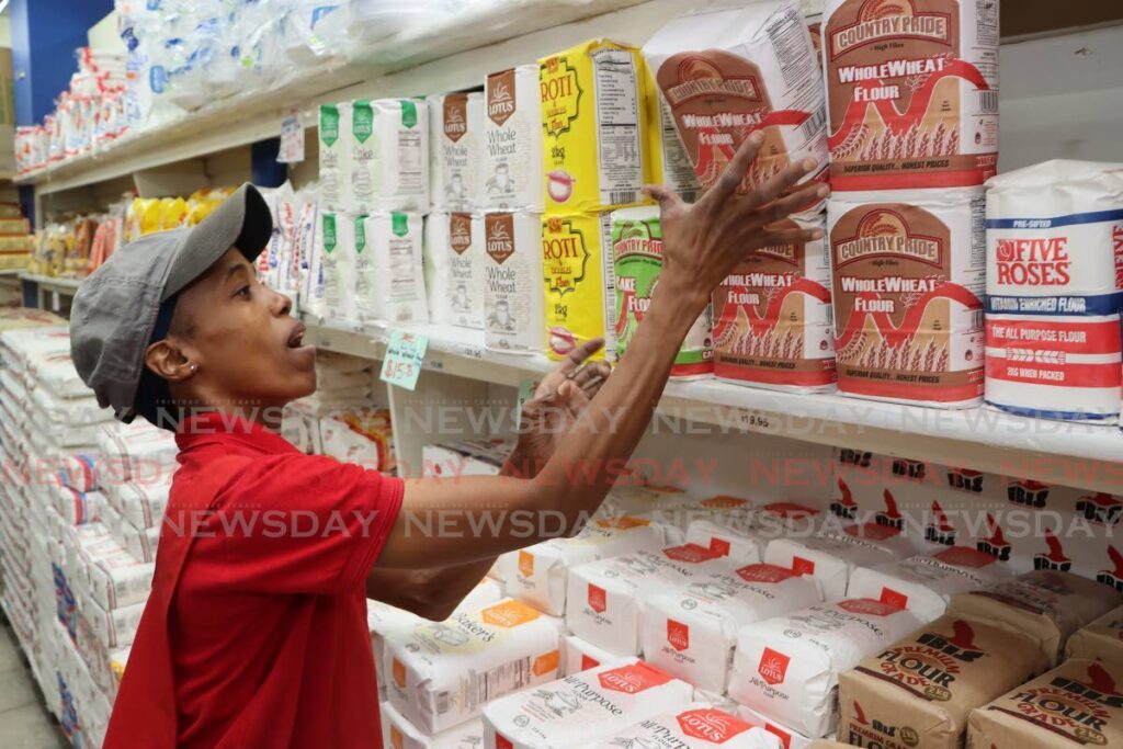 STOCKING UP: Rebecca David, an employee of Sing Chong Supermarket in Port of Spain, restocks shelves with Country Pride flour on Friday after Nutrimix announced a decrease in its flour products.  - Angelo Marcelle