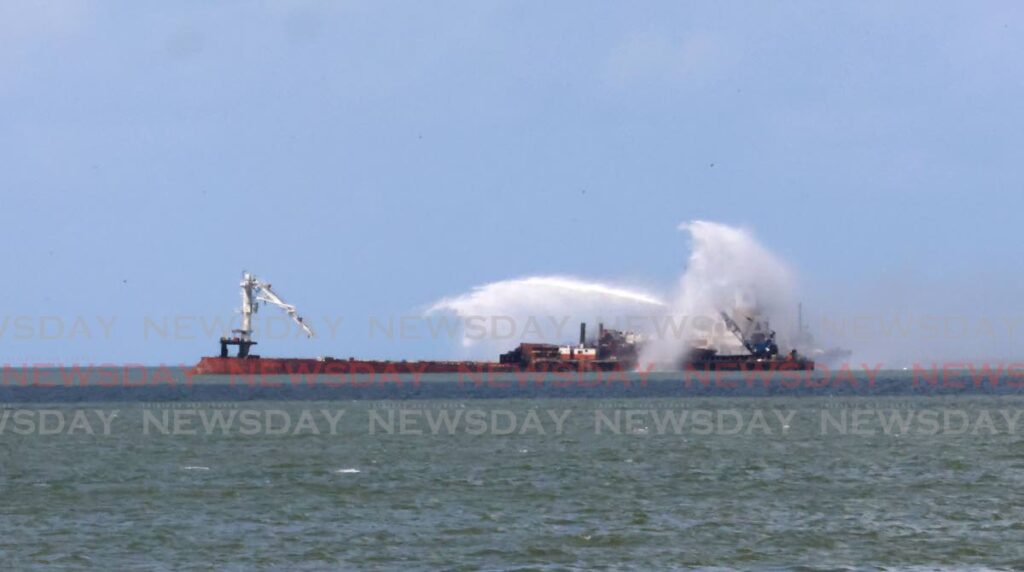 Members of the National Energy Corporation of TT's  National Energy Resilience Team, right, work to extinguish a fire on board bulk carrier AV Aqua Marine in the Gulf of Paria near the Port of Port of Spain on May 14. - Photo by Roger Jacob