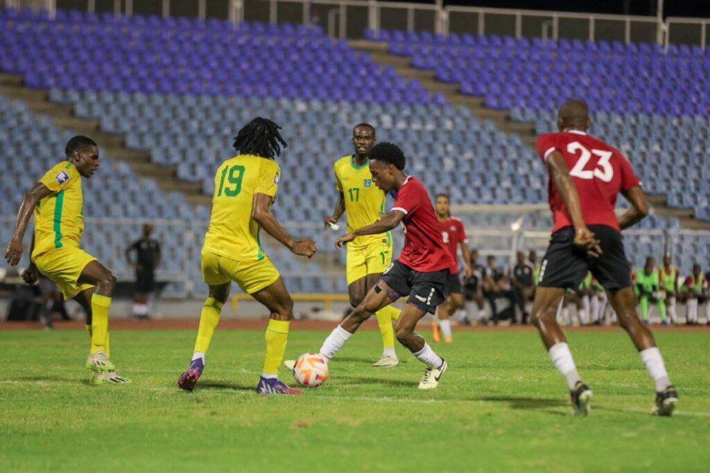 TT's Ezekiel Kesar, centre, slips a pass to Kevon Woodley, right, to score TT's second goal against Guyana during a friendly match at the Hasely Crawford Stadium, Port of Spain, on May 13. - Photo by Daniel Prentice