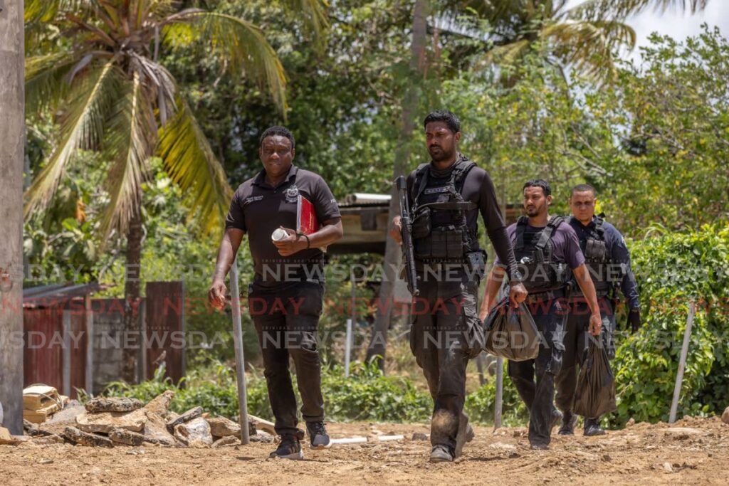 Officers leave after processing the crime scene where two men were killed by police on Dookiesingh Street, St Augustine on May 15. - Photo by Jeff K. Mayers