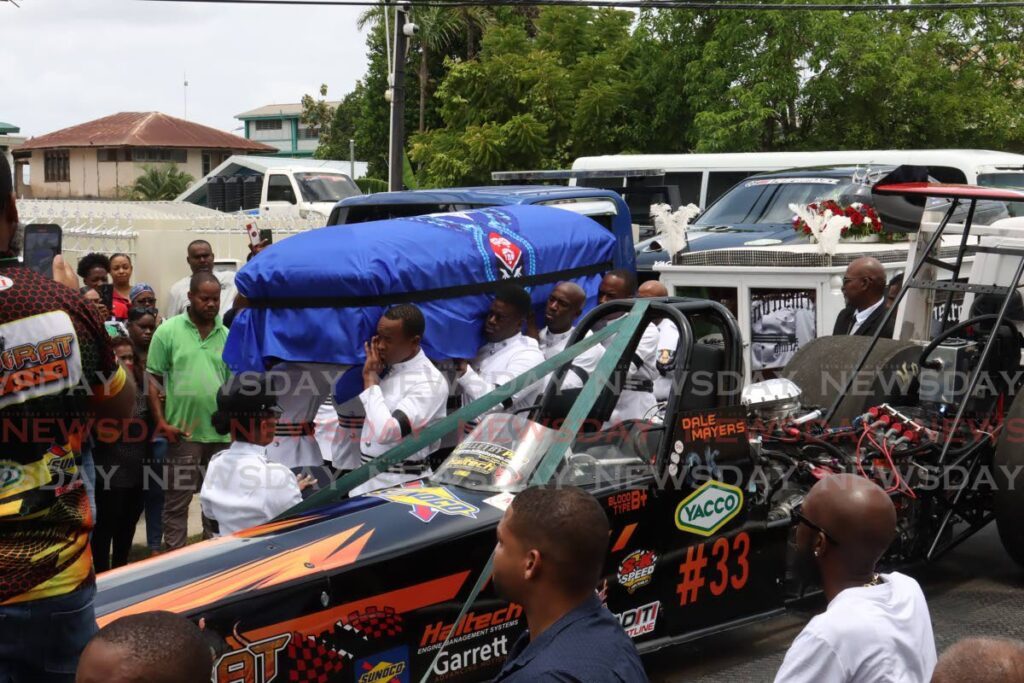 DALE'S LAST RIDE: The casket of bearing the body of drag race enthusiast PC Dale Mayers was carried alongside his race car before his funeral at the Arima Seventh-Day Adventist Church, De Gannes Street, Arima on Monday.  - Faith Ayoung