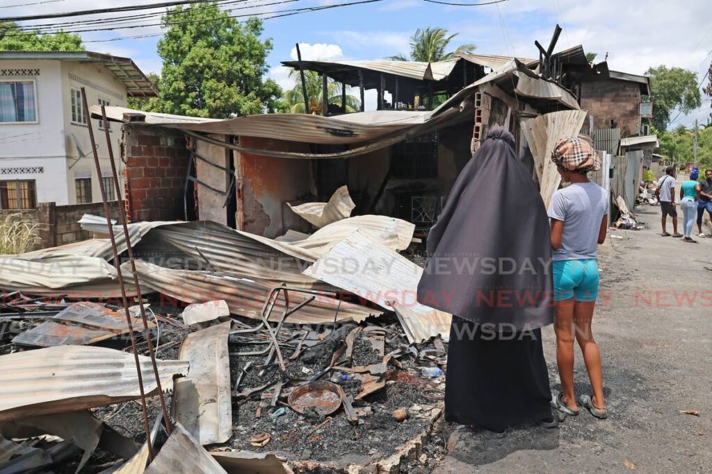 Two residents look at the damage done to four houses after a firebomb in the night on May 20. - Photo by Lincoln Holder 