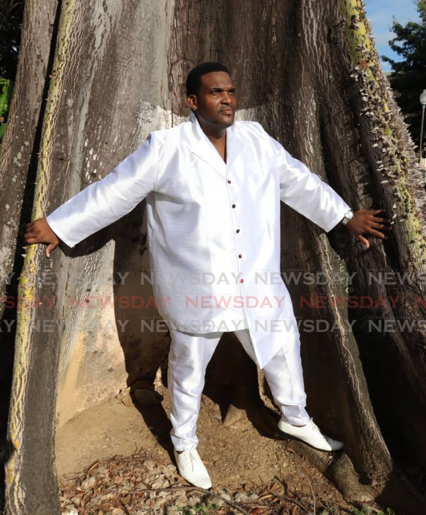 Fabrice Barker, actor, singer and Spiritual Baptist/Orisa devotee poses at the base of a silk cotton tree. - Photo by Faith Ayoung