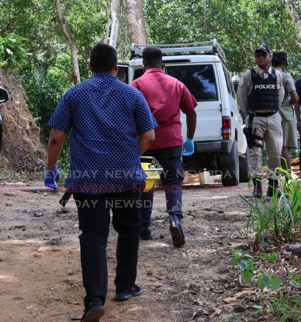 Undertakers going into a forested area in St Augustine to retrieve the bodies of four men who were killed in a shootout with police on May 23. - Photo by Roger Jacob