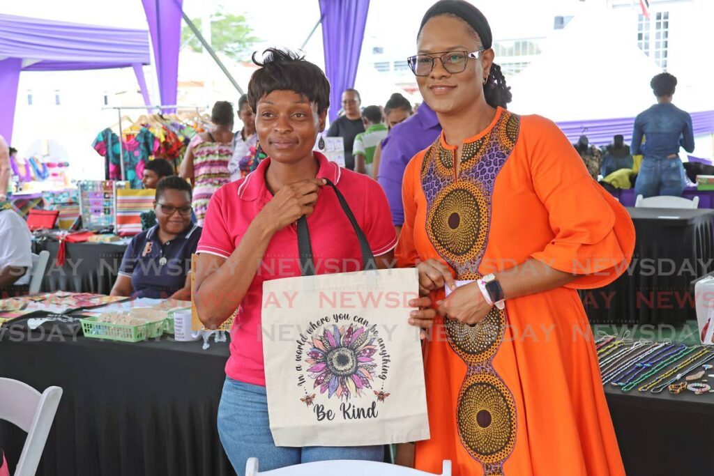 Entrepreneur Juliette Carbon shows off her product to Minister in the Office of the Prime Minister Ayanna Webster-Roy as she toured the Women's Entrepreneurial  Development and Product Expo, the Women's Village at Harris Promenade San Fernando on Wednesday. - Photo by Lincoln Holder 