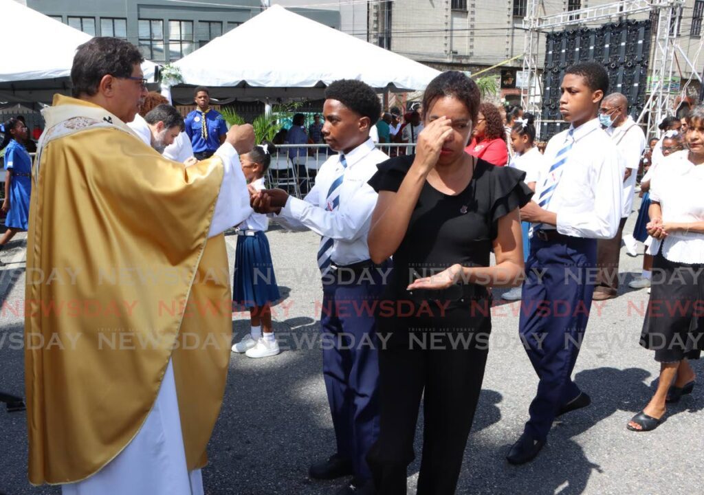 Archbishop Jason Gordon gives holy communion to worshippers during Corpus Christi mass outside the Cathedral of the Immaculate Conception in Port of Spain on Thursday. PHOTO BY ANGELO MARCELLE - Angelo Marcelle