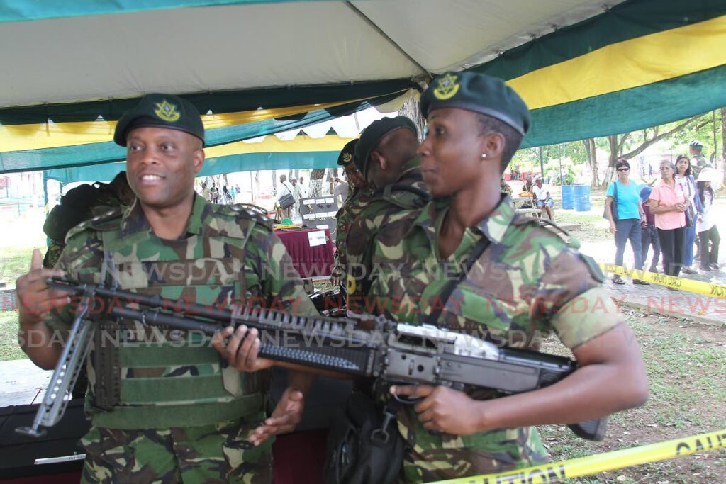In this file photo, two soldiers display one of the high-powered weapons in their arsenal during a military tattoo exhibition at Woodfrod Square, Port of Spain. - 