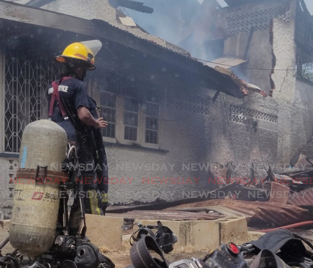 A fire officer battles the blaze at Moses Avenue, Saddle Road, San Juan on May 9. - Photo by Josette Nicole Deonanan. 