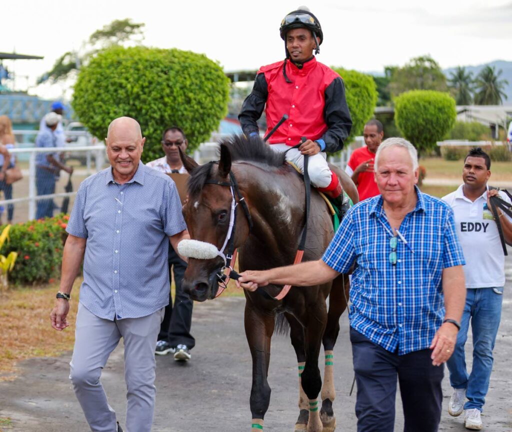 Hello World, ridden by Brian Boodramsingh, gets escorted to the winner's circle by owner Neil Poon Tip, left, and trainer John O’Brien, right, after winning the Arima Race Club Dixee Crackers Champagne Stakes at the Santa Rosa Park on March 30, 2023 in Arima. - File photo