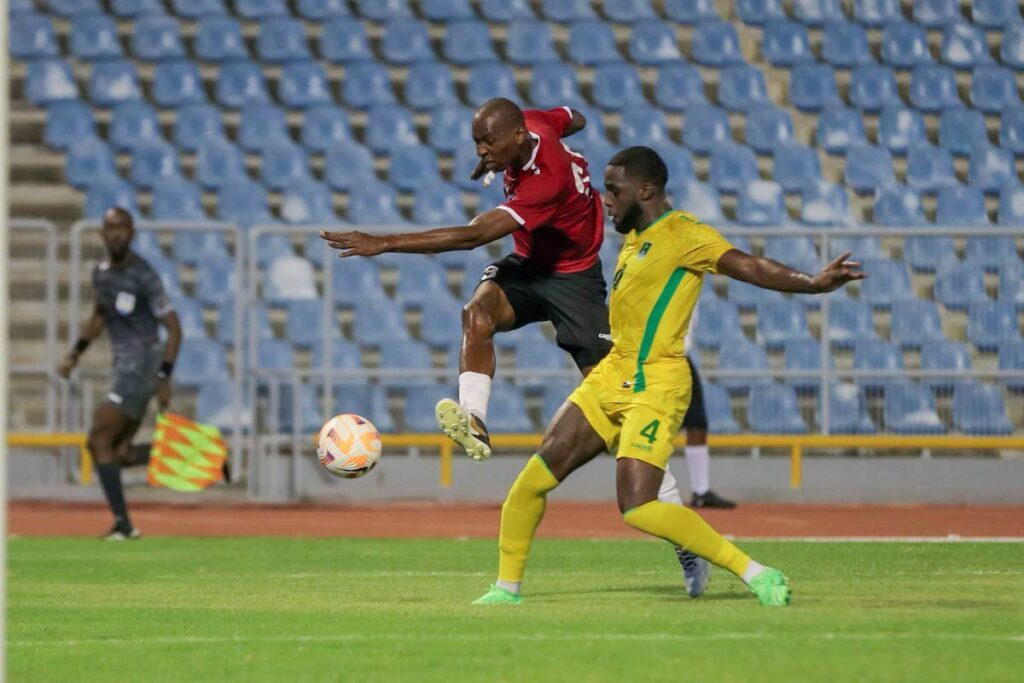 TT striker Kevon Woodley (L) shoots at goal while under pressure from Guyana’s Jeremy Grant during a friendly match at the Hasely Crawford Stadium in Port of Spain, on May 13. TT won 2-1. - Daniel Prentice