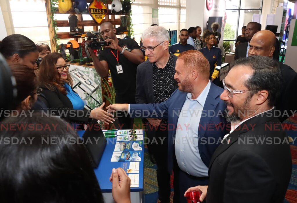 HELLO: AnsaMcAl CEO Anthony N. Sabga III greets a woman on day one of the three-day Sustainable Energy Conference on Monday at the Hilton Trinidad. At right is Energy Minister Stuart Young. - Photo by Faith Ayoung