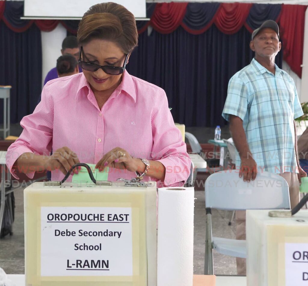 A man curiously looks at UNC political leader Kamla Persad-Bissessar as she casts her vote in her party's national executive election at the Debe Secondary School on Saturday. - Photo by Venessa Mohammed