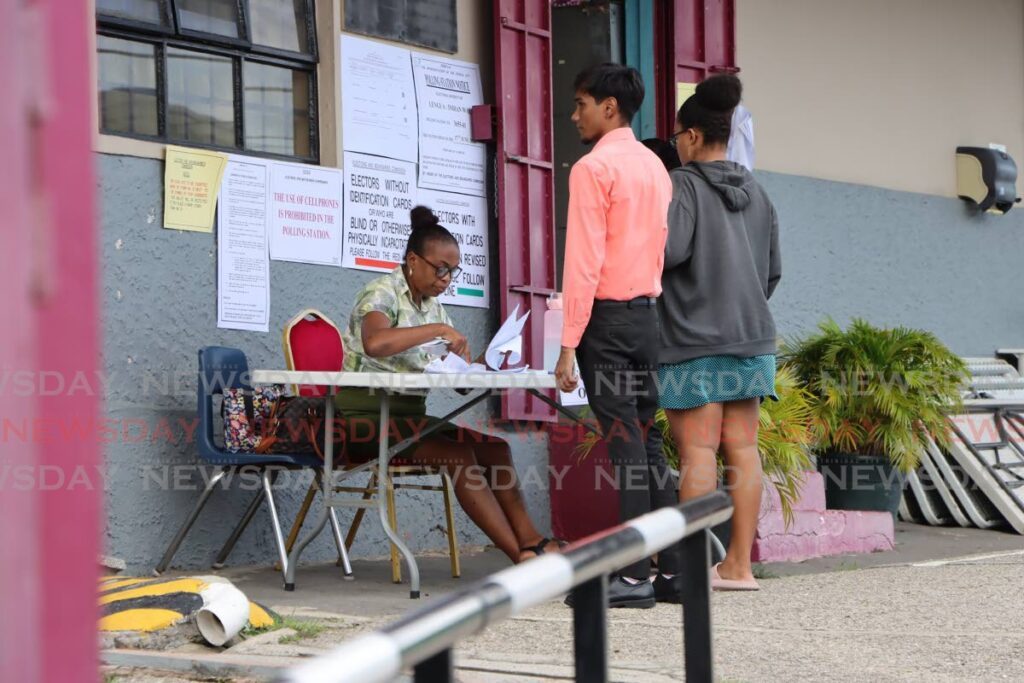 A polling officer checks the names of voters before they vote during the Lengua/Indian Walk by-elections at the St Michael's AC Primary School, Princes Town on June 17. - Photo by Ayanna Kinsale