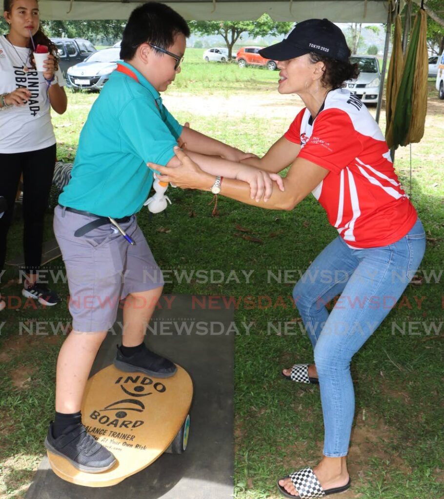 Belinda Bain-Hares of the Surfing Association of TT shows a St Patrick's Newtown Boys RC student how to balance on a surfboard, during the TT Olympic Committe Olympic Day celebrations, at the Queen's Park Savannah, Port of Spain on June 21. - Photo by Angelo Marcelle
