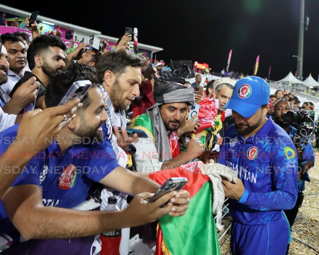 Afghanistan's captain Rashid Khan signs t-shirts for fans during the ICC T20 World Cup semifinal match against South Africa on June 26. - Photo by Ayanna Kinsale