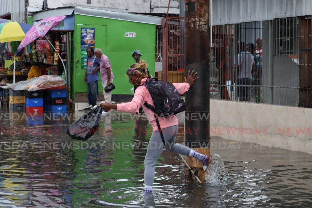 A woman braves floodwaters as she makes her way across South Quay in Port of Spain, on June 28. - Photo by Faith Ayoung