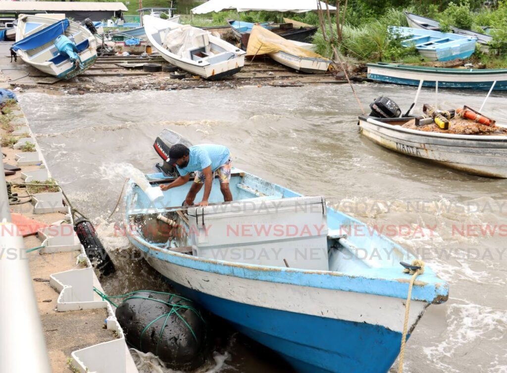 Fisherman Neil Dookie removes rainwater from his boat near the jetty at the Cocorite Fishing Facility off the Audrey Jeffers highway on July 1. - Photo by Faith Ayoung
