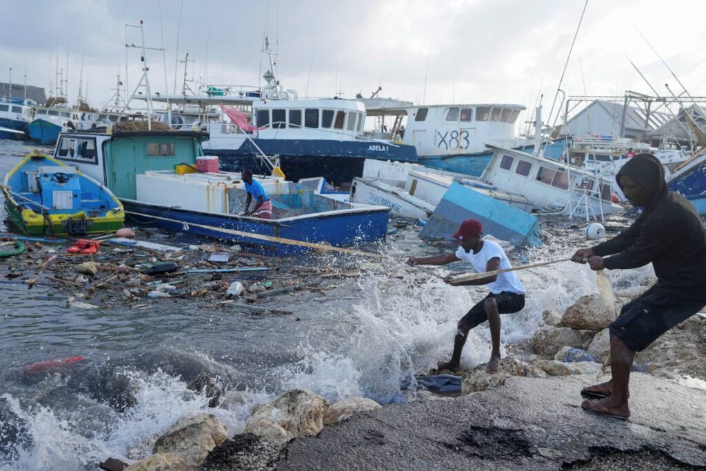 Fishermen pull a boat damaged by Hurricane Beryl back to the dock at the Bridgetown Fisheries in Barbados on Monday. - AP PHOTO