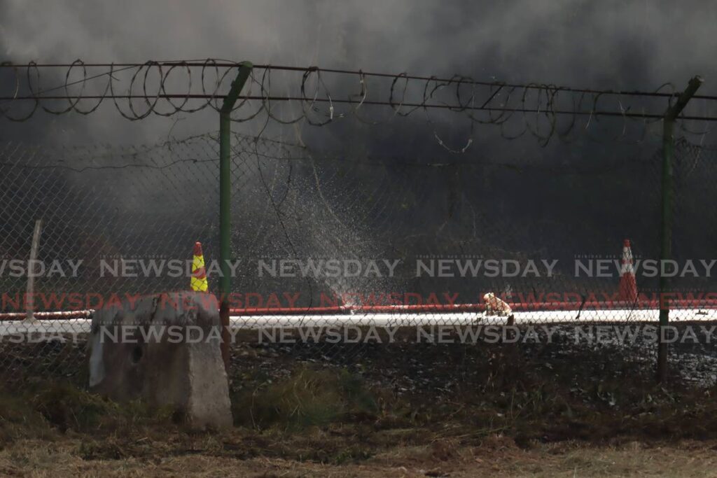 Sun shines on a leak in one of the hose as fireofficers out a fire at the compound of Caridoc, Chaguramas, July 5.