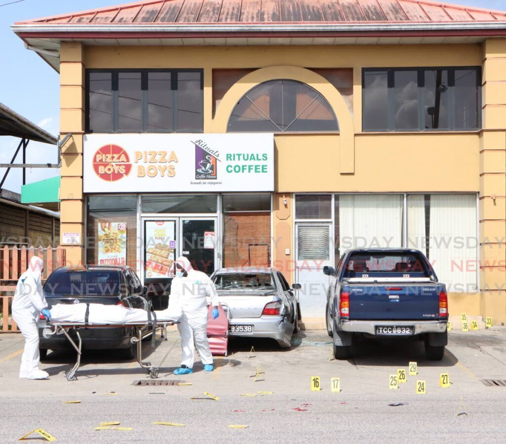 Crime scene investigators remove the body of one of the three men killed at Pizza Boys/Rituals Coffee House, on the Southern Main Road, Cunupia on July 14. - File photo by Angelo Marcelle