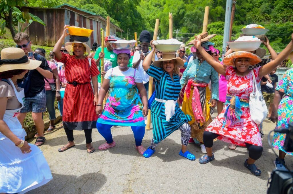 Village women carry their washing tubs on their heads as they dance on the trek during the Charlotteville Natural Treasures Day on July 15.  - Photos by Visual Styles