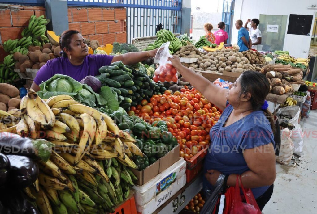 Market vendor Sharrie Singh, left, sells her tomatoes to a customer at the Arima Central Market in Arima on July 17. - Photo by Roger Jacob