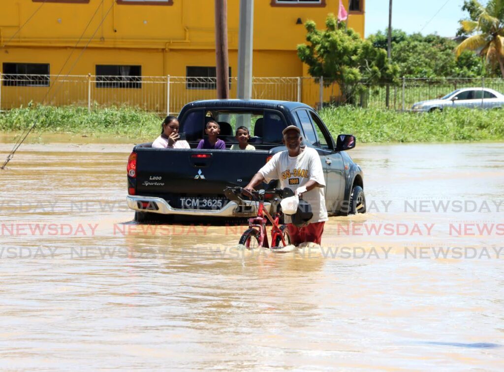 A resident walks through flood waters at Rochard Douglas Road, Barrackpore on July 17.  -Photo by Ayanna Kinsale 