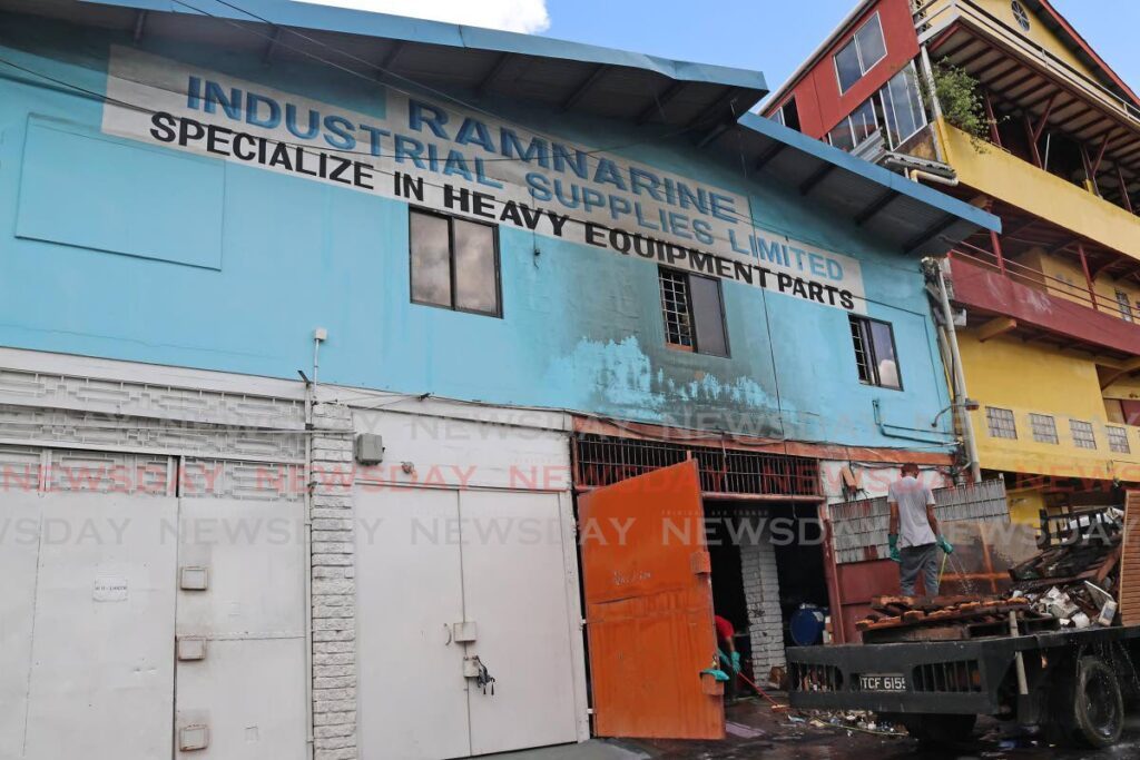 Workers on July 19 remove debris from Southern Systems Ltd at Adesh Drive, Duncan Village San Fernando after a fire which also affected Ramnarine Industrial supplies on July 18. - Photo by Lincoln Holder 