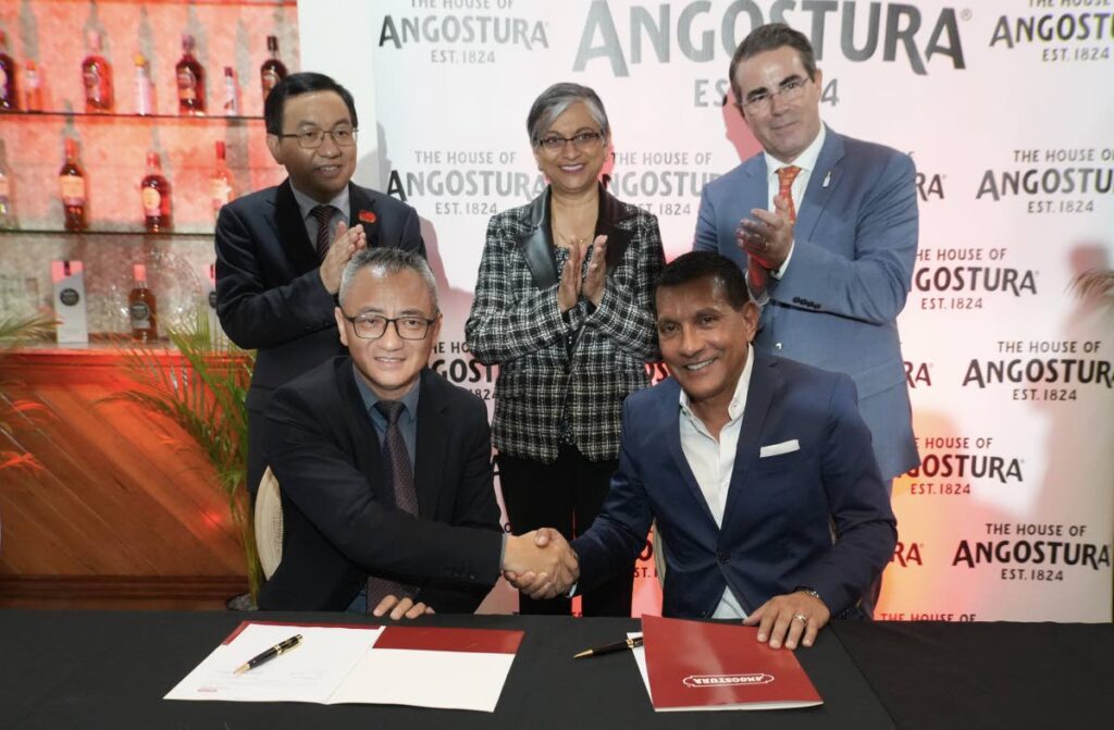 SEAL THE DEAL: Charles Xiang Cheng, managing director of Caribbean Commercial Management (Hangzhou) Co Ltd, left, and Terrence Bharath, chairman of Angostura Holdings Ltd, sealed the distribution agreement deal with a handshake on July 19.
In the back row are Fang Qiu, Chinese ambassador, left, Ava Mahabir-Dass, deputy permanent secretary at the Trade Ministry and Laurent Schun, Angostura's CEO. - Photo courtesy Angostura 