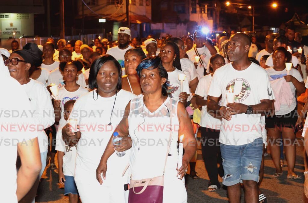 Jean McLeod, centre, mother of Mango Rose murder victim Kerwin McLeod, is supported by relatives as she leads a candlelight vigil and procession hosted by Massy Trinidad All Stars Steel Orchestra beginning at the band's panyard on Duke Street, Port of Spain on July 23. The vigil was held in honour of All Stars members McLeod and Jean-Marc Fonrose who were both murdered by gunmen on July 12. - Photo by Roger Jaocb