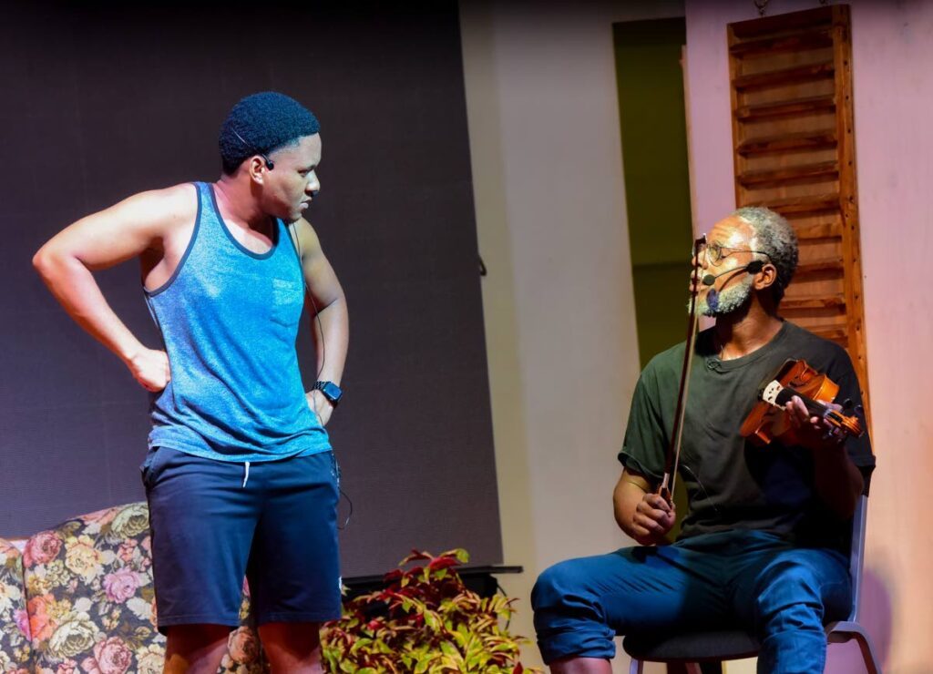  Jomo (Daniel Wilson), left, is given a lesson in playing an instrument from villager Cuthbert (Albert Grieg) at Mt St George's heritage presentation, We Tambrin Story, on July 24, at the Hope Community Centre. - Visual Styles