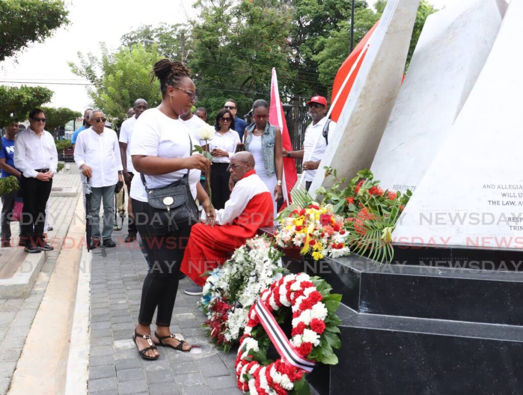 Afeisha Caballero places a white rose in honour of her mother, Lorraine Caballero, a parliamentary clerk killed during the attepmted coup at the Red House. She was among people gathered at the cenotaph on July 27 to mark the 34th anniversary of the insurrection. - Photo by Faith Ayoung