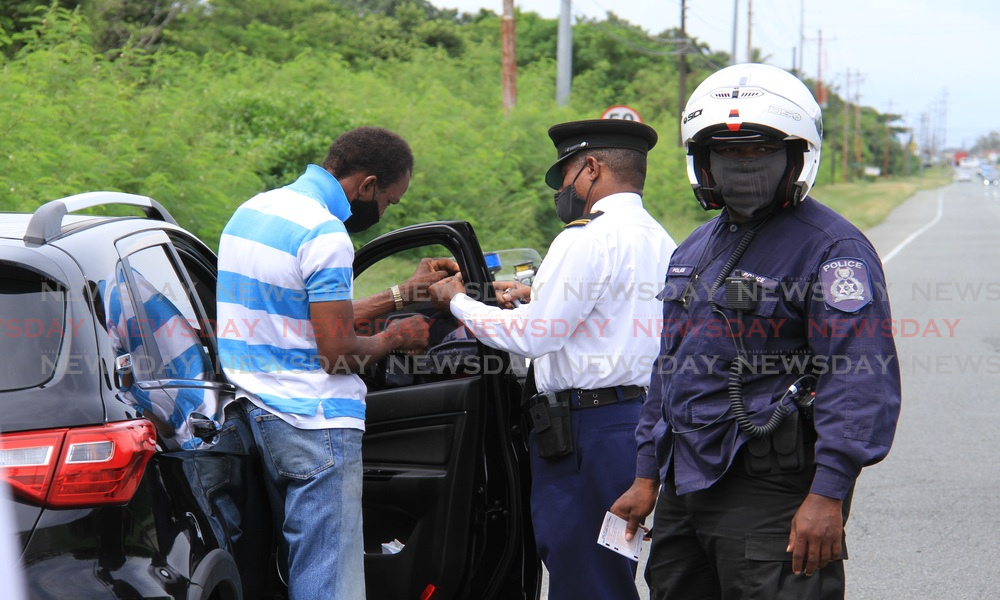 A license officer assists this motorist with removing the heavy tint from his vehicle on Milford Road, Tobago in 2020. New tint regulations take effect on July 29.  - FILE PHOTO 