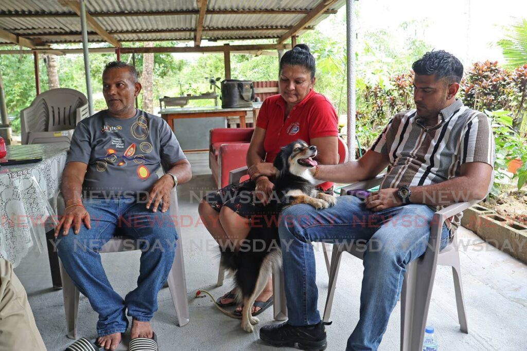 In this file photo, parents Ramesh Bobby Ramnanan, Soma and son Rishi talk about their last moments with Ryan Ramnanan who, alongside his best friend Sachin Teeluckdharry, was found dead in an overturned vehicle in the Cipero River off the Solomon Hochoy Highway on August 4. Also in the photo is Ryan's dog Sophie.   - Photo by Lincoln Holder 