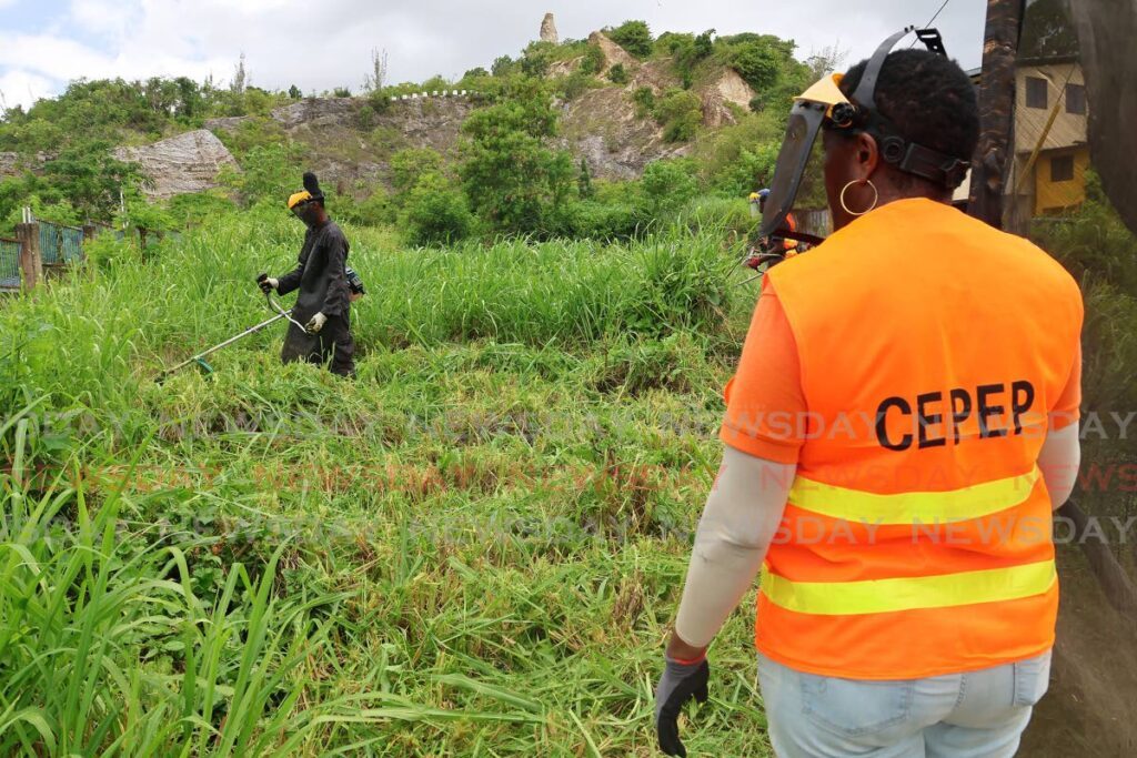 CEPEP workers clearing an open lot of land along Circular Road, San Fernando as part of the Ministry of Rural Development and Local Government's Cut and Clear Initiative to combat dengue in communities on August 7. - Photo by Lincoln Holder 