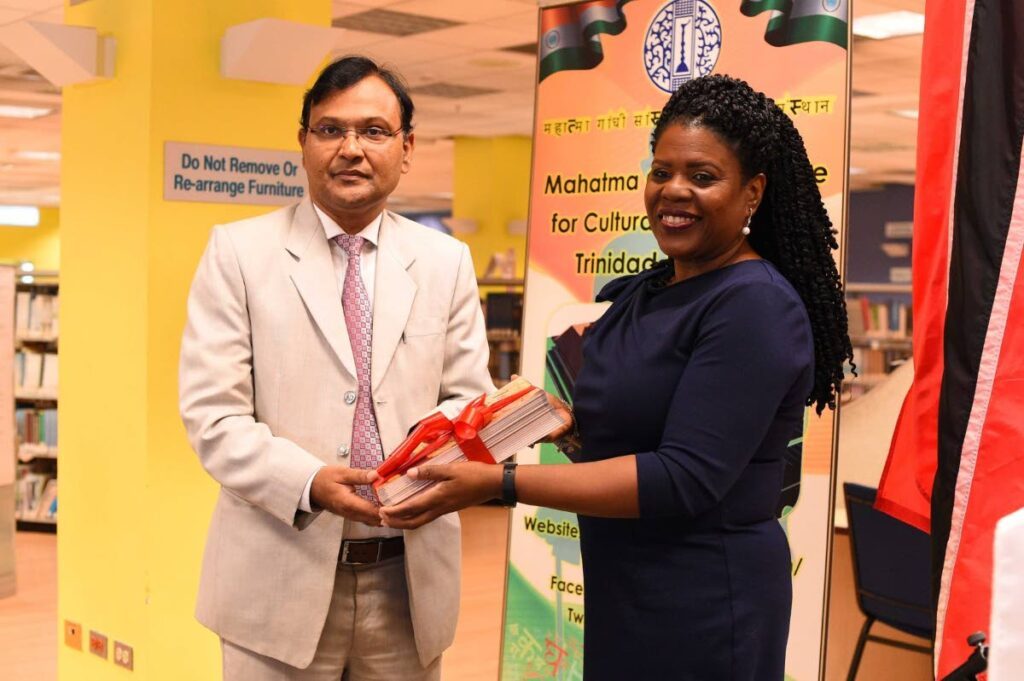 Nalis’ executive director Paula Greene presents copies of Nalis’ publication titled Indo-Trinbagonian Poetry to Dr  Pradeep Rajpurohit, High Commissioner for India at the launch of the Indian Corner. - 