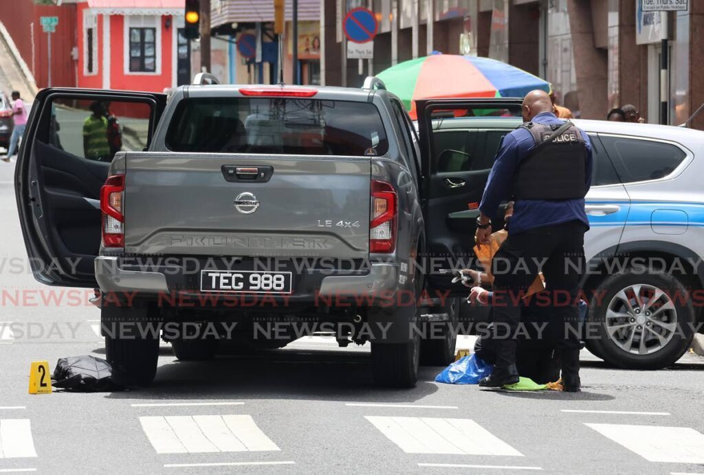 A crime scene investigator removes the fire arm used by the robbery suspects on August 15. - Photo by Roger Jacob