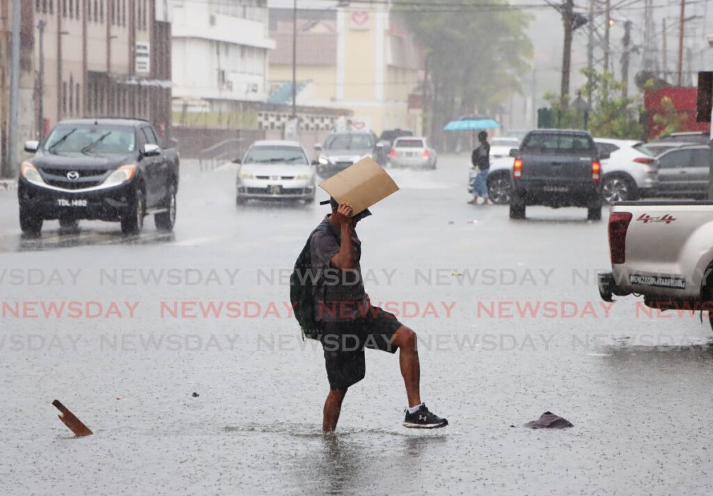 A man makes his way through flood waters near City Gate, Port of Spain on August 15.  - File photo by Ayanna Kinsale