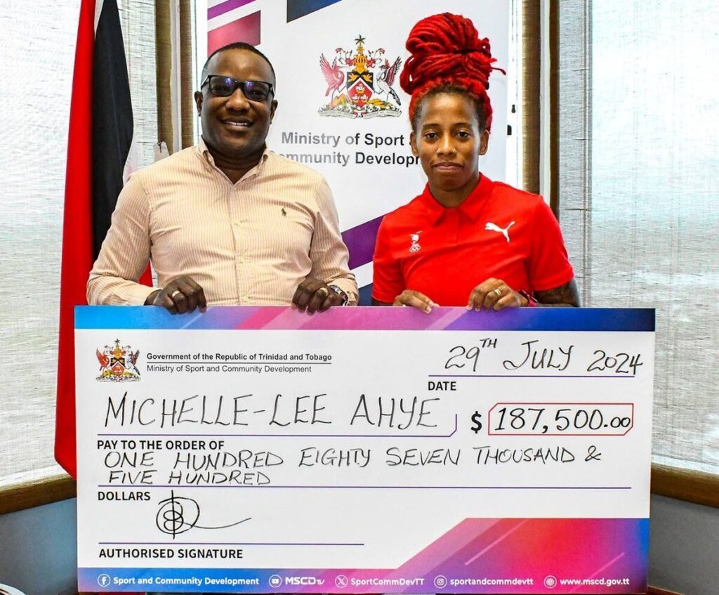 Olympic sprinter Michelle-Lee Ahye, right, collects a cheque from David Roberts, acting permanent secretary, Ministry of Sport and Community Development, on April 15 at the ministry in Port of Spain.  - 