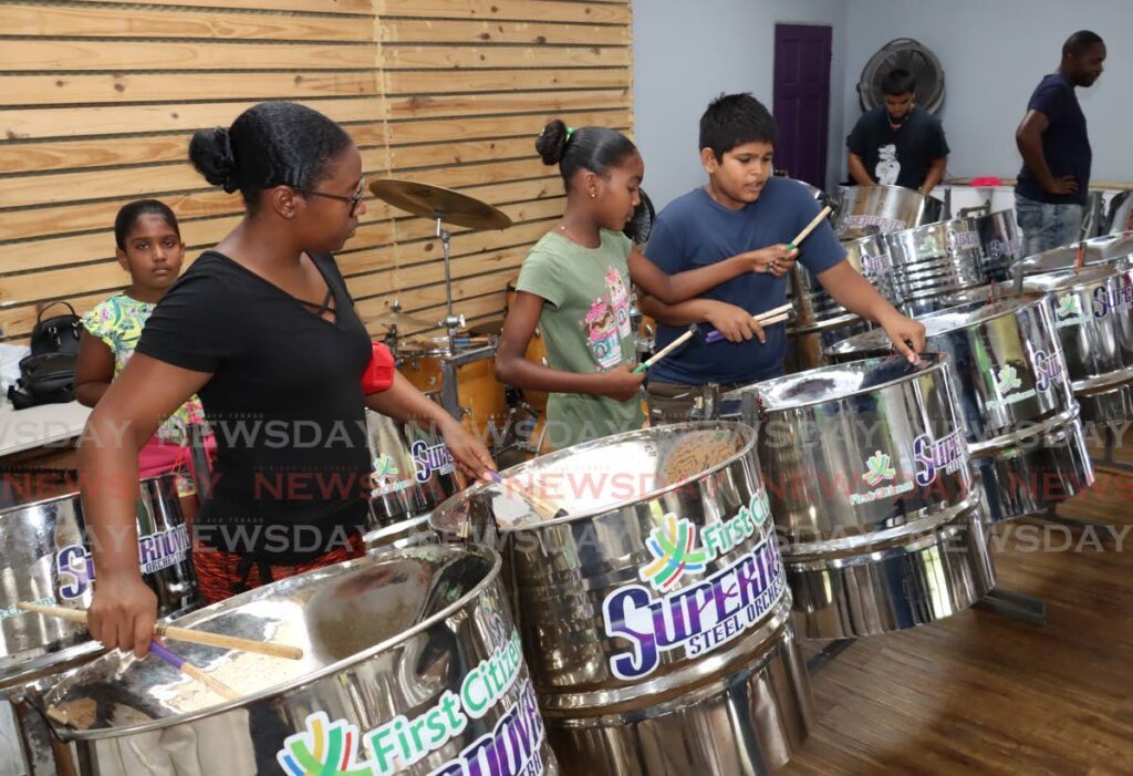 From left, Derriann Dyett teaches Arianna Liverpool, 10, and Rauul Ramoutar, 13, how to strike the notes. - Photo by Faith Ayoung