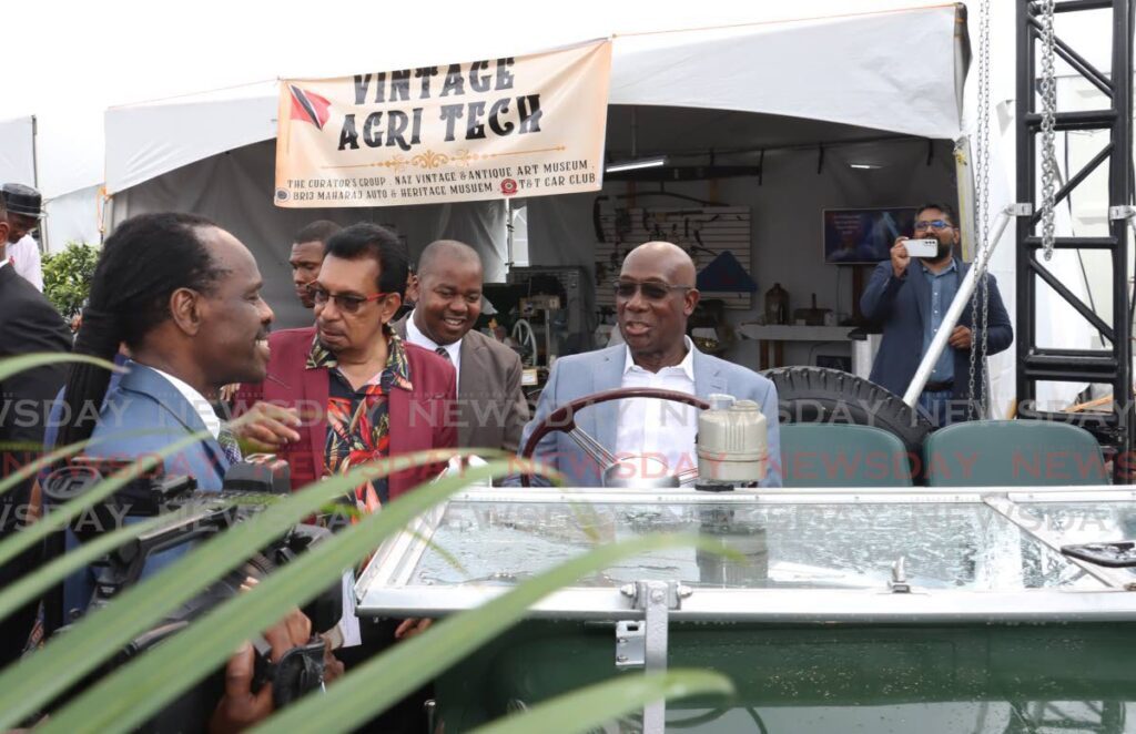 The Prime Minister, right, sits in a vintage Land Rover at the Vintage Agri Tech booth at Agri-Expo 2024 at the Queen’s Park Savannah. - Photo by Faith Ayoung