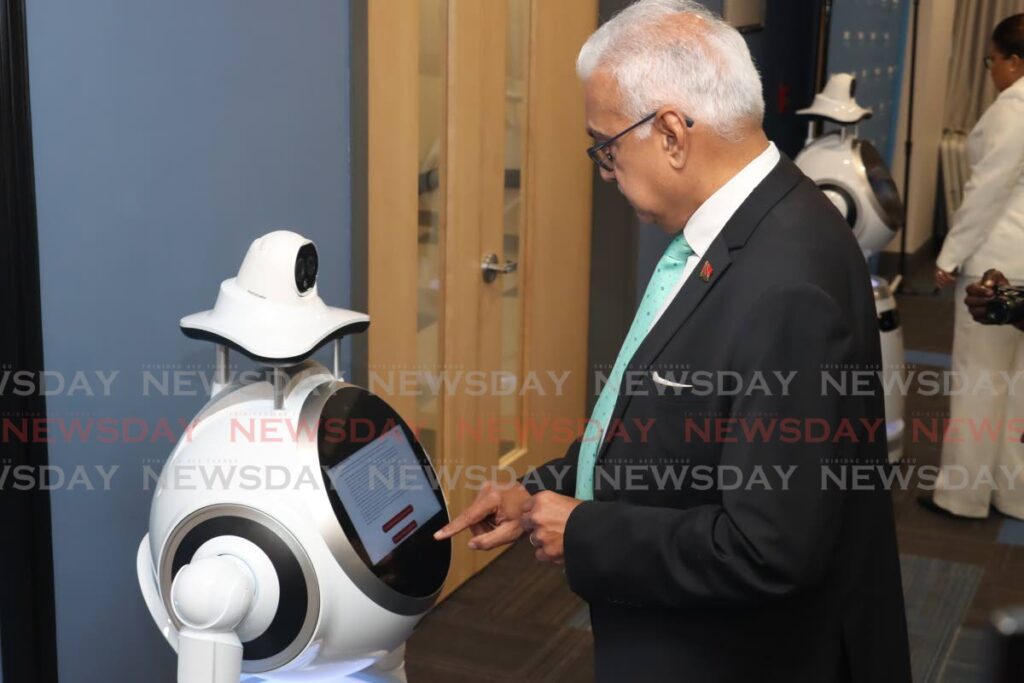 Health Minister Terrence Deyalsingh interacts with a robot at the health service robots handover ceremony at the Ministry of Health, Queen's Park East, Port of Spain, on August 17. - Photo by Faith Ayoung