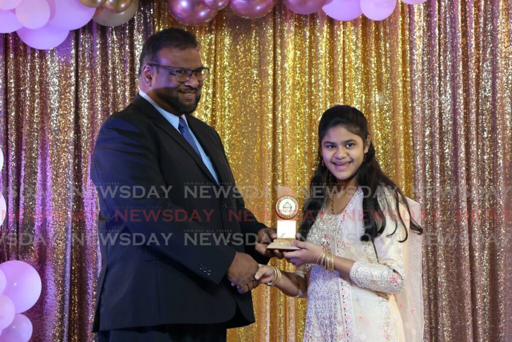 From left, Intikhab Hassan presents Salina Lutchman of Carapichaima ASJA primary school with an award for placing first in her school at the 2024 SEA examinations.  - Photo by Lincoln Holder 