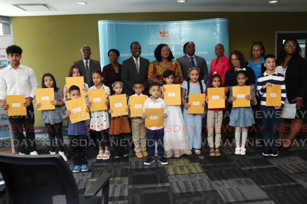 SCHOOL-TIME: Migrant children with their exemption letters to attend school at the Ministry of Education building, St Vincent Street, Port of Spain on August 19. In the back row, third from left are National Security Minister Fitzgerald Hinds, Education Minister Dr Nyan Gadsby-Dolly and Minister in the Ministry of National Security Keith Scotland.  - Photo by Gabriel Williams